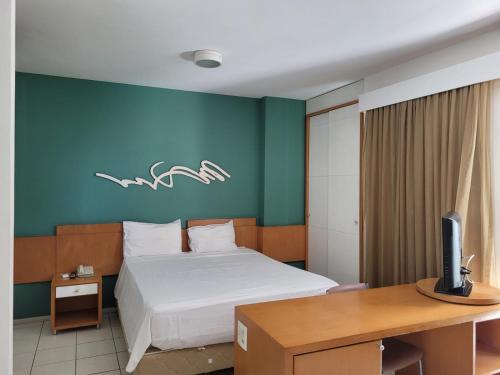 维多利亚Praia do Canto Apart Hotel - Apto 405 - Varanda Lateral com Vista Mar的一间卧室配有一张床和一张书桌及电视