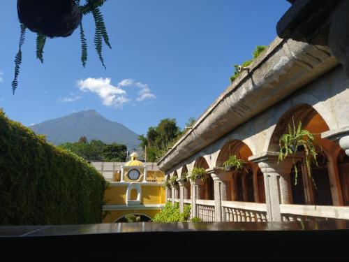 危地马拉Ciudad Vieja Bed & Breakfast Hotel的一座建筑,上面有钟,后面有山