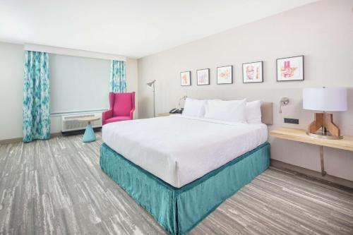 瑟普赖斯Hilton Garden Inn Surprise Phoenix的酒店客房,配有一张床和一张粉红色的椅子