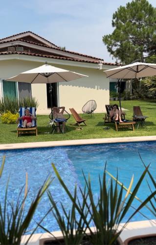 阿吉吉克Quinta Los Caballos的房屋旁的游泳池配有椅子和遮阳伞