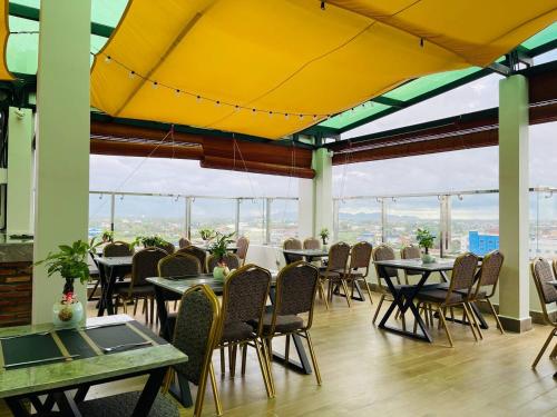 贡布The Square Kampot Hotel的餐厅设有桌椅和黄色天花板