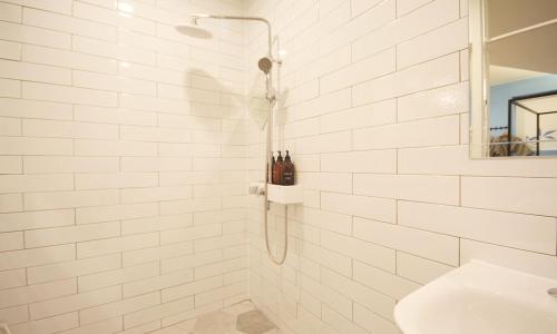 IksanIksan 4 Seasons Hotel的带淋浴和盥洗盆的白色瓷砖浴室