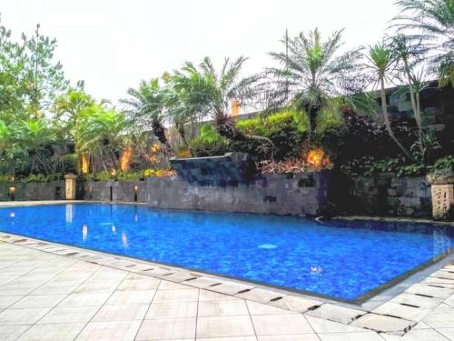 万隆Cottonwood Japandi Apartment at Majesty 509的一座大型蓝色游泳池,拥有石墙和棕榈树
