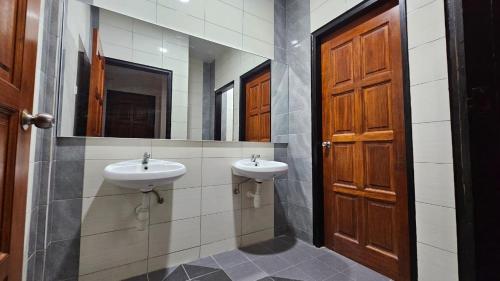 瓜埠Rumah Amaan的一间带两个水槽和木门的浴室