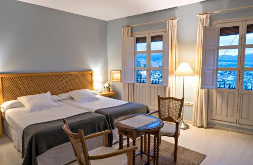 格拉纳达卡门卡拉科尔水塔酒店的一间卧室配有两张床和一张桌子及椅子