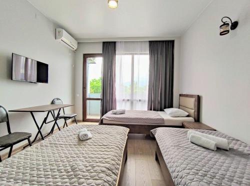 科布列季Elgabi Hotel Kobuleti的客房设有两张床、一张桌子和一张书桌。
