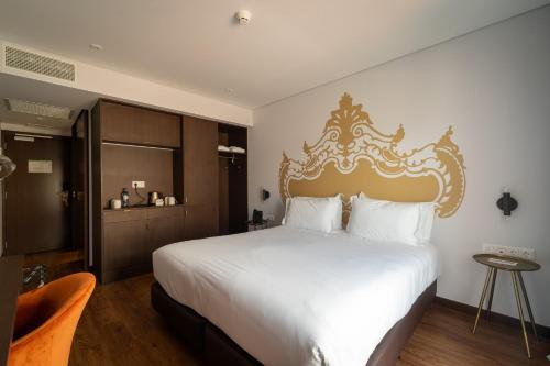 英雄港Palacio Santa Catarina Hotel的一间卧室配有一张白色大床和金色床头板