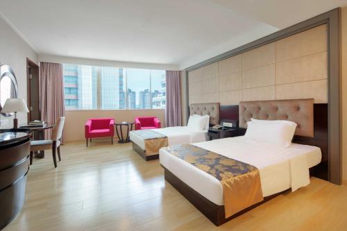 Shunde佛山冠新酒店的酒店客房带两张床和一张桌子以及椅子。