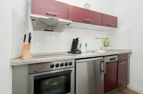 汉堡Appartements in der historischen Deichstrasse contactless Check in的厨房配有红色橱柜和不锈钢烤箱