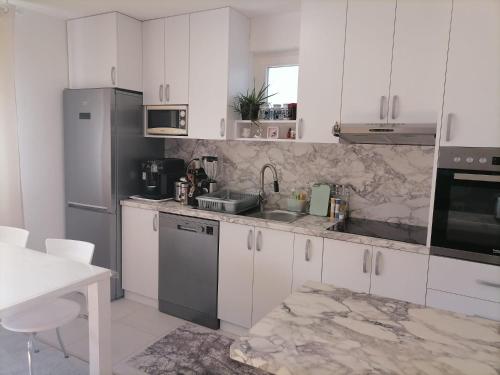 SurčinAirport Apartment的厨房配有白色橱柜和不锈钢用具