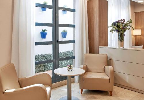 瓦伦西亚NH瓦伦西亚科学酒店的一间等候室,配有两把椅子、一张桌子和一个窗户