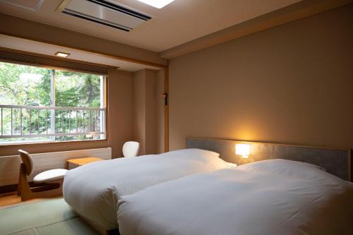 札幌Hatagoya Jozankei Shoten-Adult Only的酒店客房设有两张床和窗户。