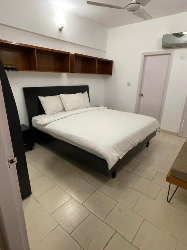 卡拉奇Ghumo - DHA Near Sea View Serviced Apartments的一间卧室配有一张带白色床单的大床