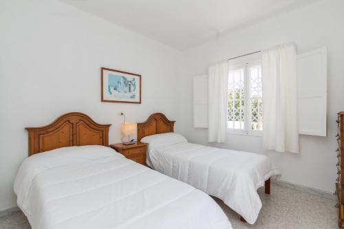 帕尔马海滩Villa los brezos的卧室设有两张床,拥有白色的墙壁和窗户。