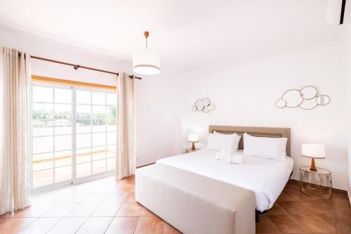 阿尔布费拉Villa Isabella的白色的卧室设有一张大床和一个大窗户