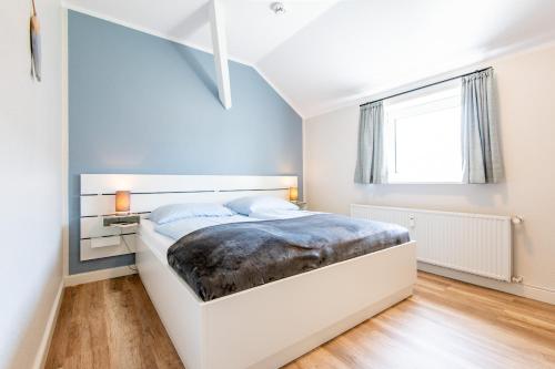 兰图姆Steger-Hüs Wohnung 35的卧室配有白色大床和蓝色的墙壁