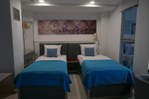 比托姆ROOMS BYTOM的小客房内的两张床,配有蓝色的床单