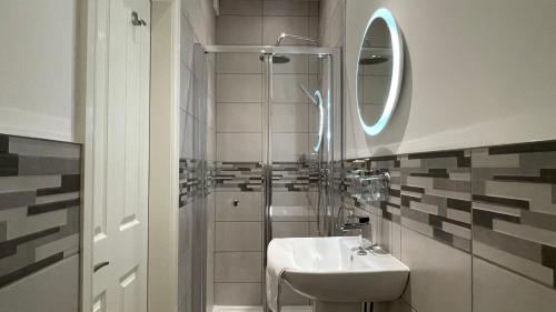 利物浦ANFIELD PLACE TO STAY的浴室配有盥洗盆和带镜子的淋浴