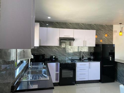 恩多拉Swiss Luxury Apartments的厨房配有白色橱柜和黑色家电