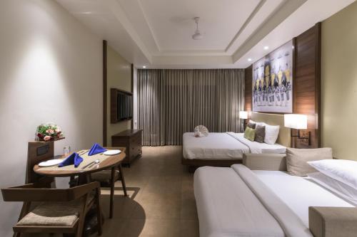 NīndakaraClub Mahindra Ashtamudi的酒店客房设有两张床和一张桌子。
