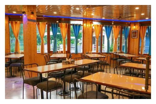 阿尔莫拉Shivalik River Retreat的餐厅设有木桌、椅子和窗户。