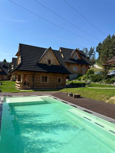 Białka TatrzanskaDomki w Białce WOODHOUSE- basen, sauna, jacuzzi的房屋前有游泳池的房子