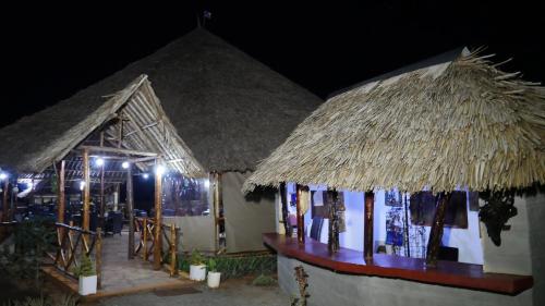 VoiTausa Tsavo Eco Lodge的两座晚上有稻草屋顶的小建筑