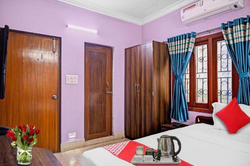 加尔各答Flagship Himgiri Guest House的卧室设有紫色墙壁、一张床和一张桌子
