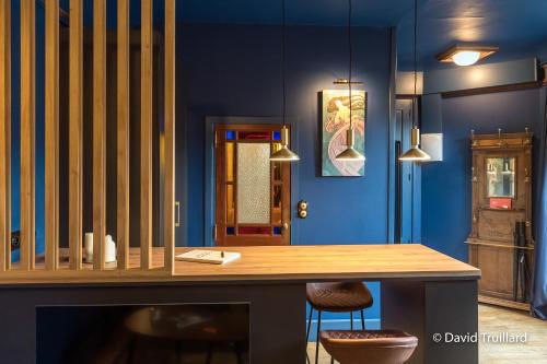 沙勒维尔-梅济耶尔Suites Mana- Le Boudoir Art Déco 4* Place Ducale Parking inclus的一间拥有蓝色墙壁和木桌的用餐室