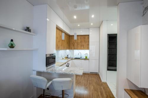 利沃夫Best view apartments的厨房设有白色的墙壁、木制橱柜和白色的凳子