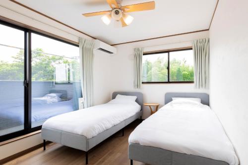 Kōembō三浦海岸 SealightVilla A棟的配有窗户和吊扇的客房内的两张床