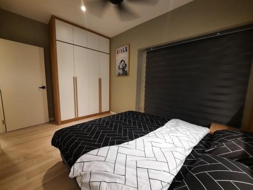 马六甲Melaka Homestay Best in Town 6+3 paxs的一间卧室配有一张带黑白色棉被的床
