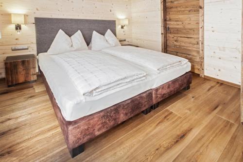 萨尔巴赫Kendlalm的卧室内的一张大床,铺有木地板