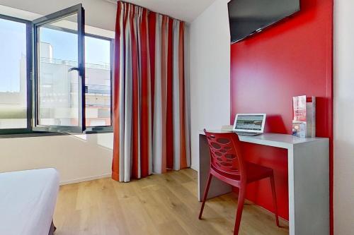 塞纳河畔伊夫里城市艾弗里酒店的一间设有书桌和红色墙壁的客房