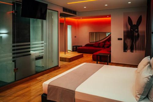 雅典派内斯酒店的一间卧室配有一张床和一张红色的沙发