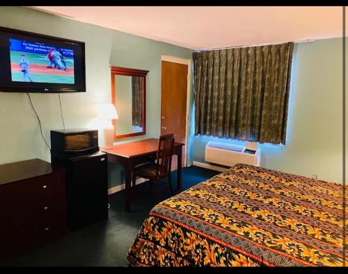 格林维尔Economy Inn of Greenville, Near ECU Health Center的酒店客房配有一张床、一张书桌和一台电视。