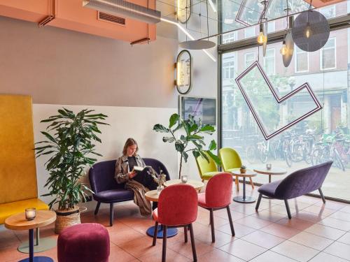 鹿特丹鹿特丹市中心旅舍的坐在沙发上,坐在桌椅的房间的女人