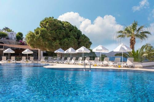 博德鲁姆Holiday Inn Resort Bodrum, an IHG Hotel- Ultra All Inclusive的一个带白色遮阳伞和椅子的大型游泳池