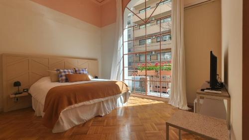 布宜诺斯艾利斯Casa Par Grand Suites的一间卧室设有一张床和一个大窗户