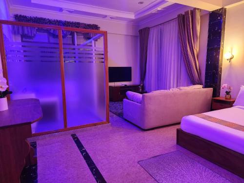 达累斯萨拉姆The Vatican Experience的一间卧室配有一张床和一张沙发,拥有紫色的灯光