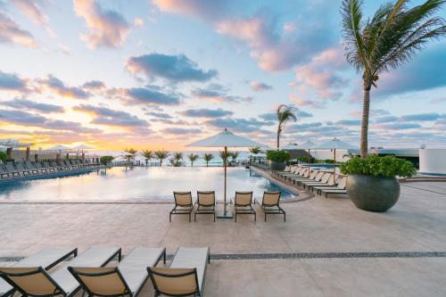 坎昆Seadust Cancun Family Resort - All Inclusive的一个带游泳池、椅子和棕榈树的度假村