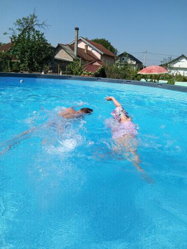 KaranacApartments Bakine Čarolije的两个人在游泳池游泳