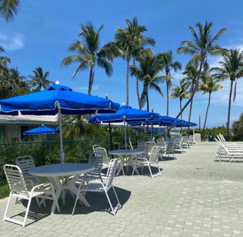 迈阿密Silver Sands Beach Resort的一排带蓝色遮阳伞的桌椅