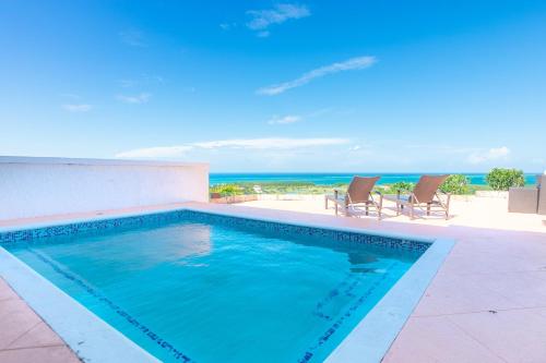 罗阿坦Pristine Bay 1303 villa的一个带椅子的游泳池,背景是大海