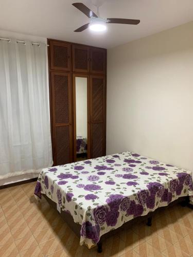 瓜拉派瑞APARTAMENTO PRAIA DO MORRO, 04 QUARTOS, ATE 10 PESSOAS.的一间卧室配有一张带紫色和白色毯子的床