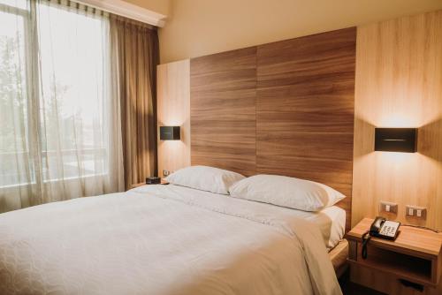 康塞普西翁Mercure Concepcion的一间卧室配有一张大床和木制床头板