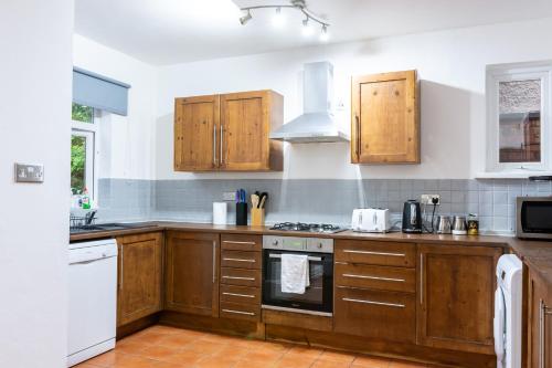 诺丁汉Mapperley Park Guesthouse的厨房配有木制橱柜和炉灶烤箱。