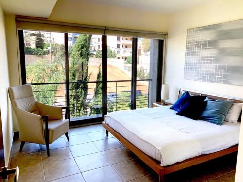 安曼Sleek & Cozy Apartment with Pool & Patio In Abdoun的一间卧室配有一张床、一把椅子和一个大窗户