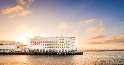 奥克兰奥克兰希尔顿酒店的水面上一座白色的大建筑,享有日落美景