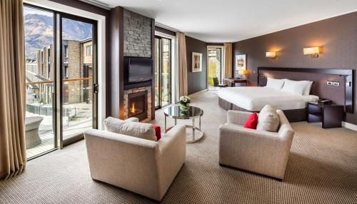 皇后镇皇后镇希尔顿酒店的酒店客房配有一张床铺、椅子和一个壁炉